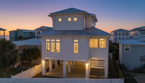 Une maison à deux étages dotée d’un balcon, de nombreuses fenêtres et d’un porche.