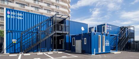 Un hotel de diseño moderno, con un edificio de varios pisos y un estacionamiento con contenedores azules.