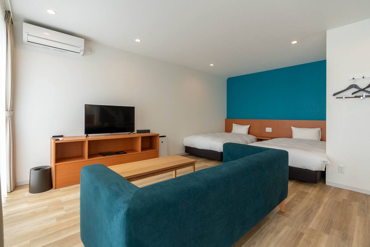 Una habitación de hotel moderna con cama, televisor, sofá y escritorio.