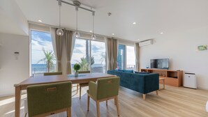 Uma sala de estar moderna com área de jantar, janelas amplas e vista para o mar.
