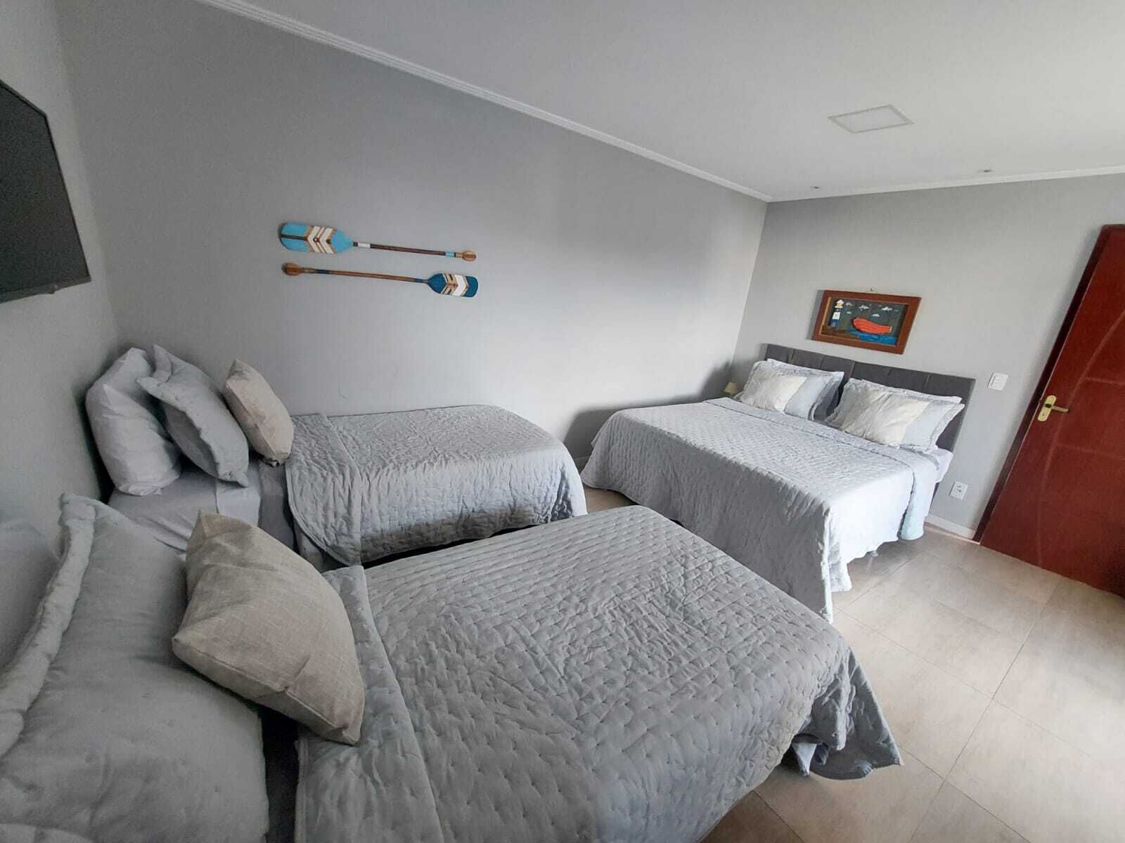 Un dormitorio con dos camas, un televisor montado en la pared y una puerta.