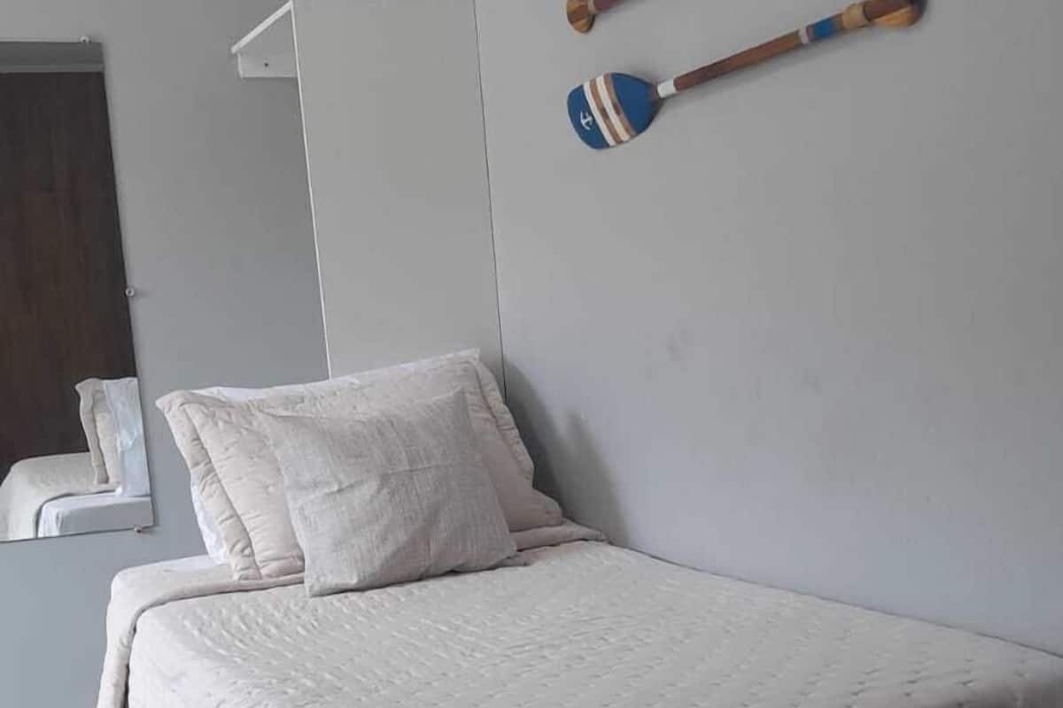 Une chambre à coucher avec un lit, des oreillers, une table de chevet, un miroir et deux maillets en bois accrochés au mur.