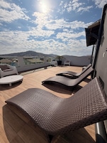 Una terraza en la azotea con sillones de mimbre, una planta en maceta y vistas de la ciudad.
