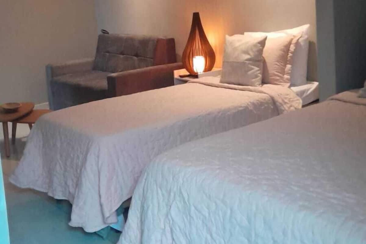 Une chambre d’hôtel avec deux lits, une table de chevet, une lampe et une chaise.
