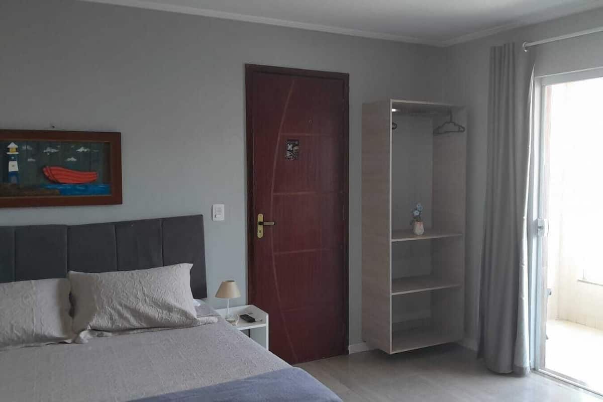 Une chambre à coucher avec un lit, une armoire, une porte et une fenêtre.