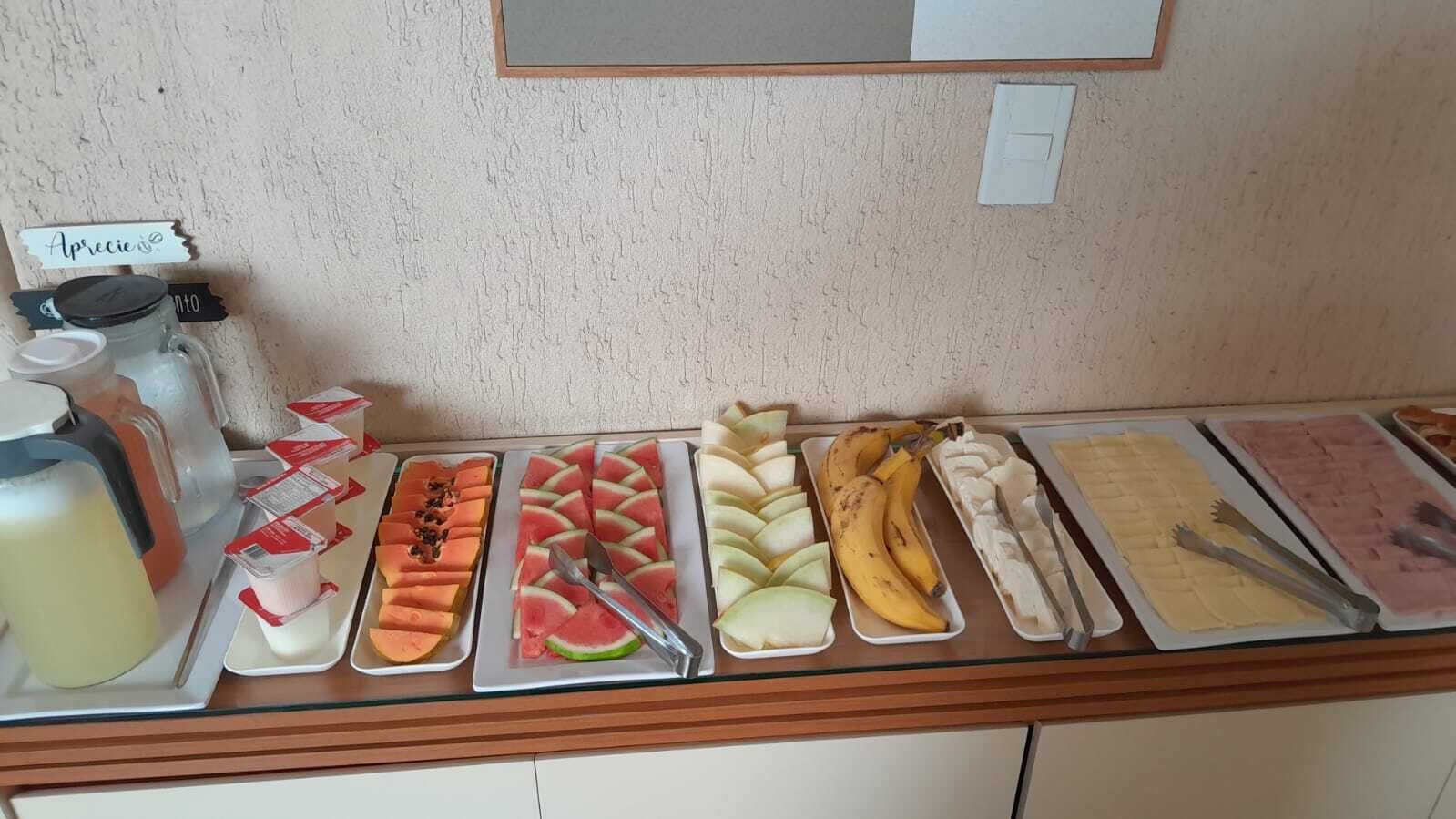A breakfast buffet with various fruits, pastries, and beverages.