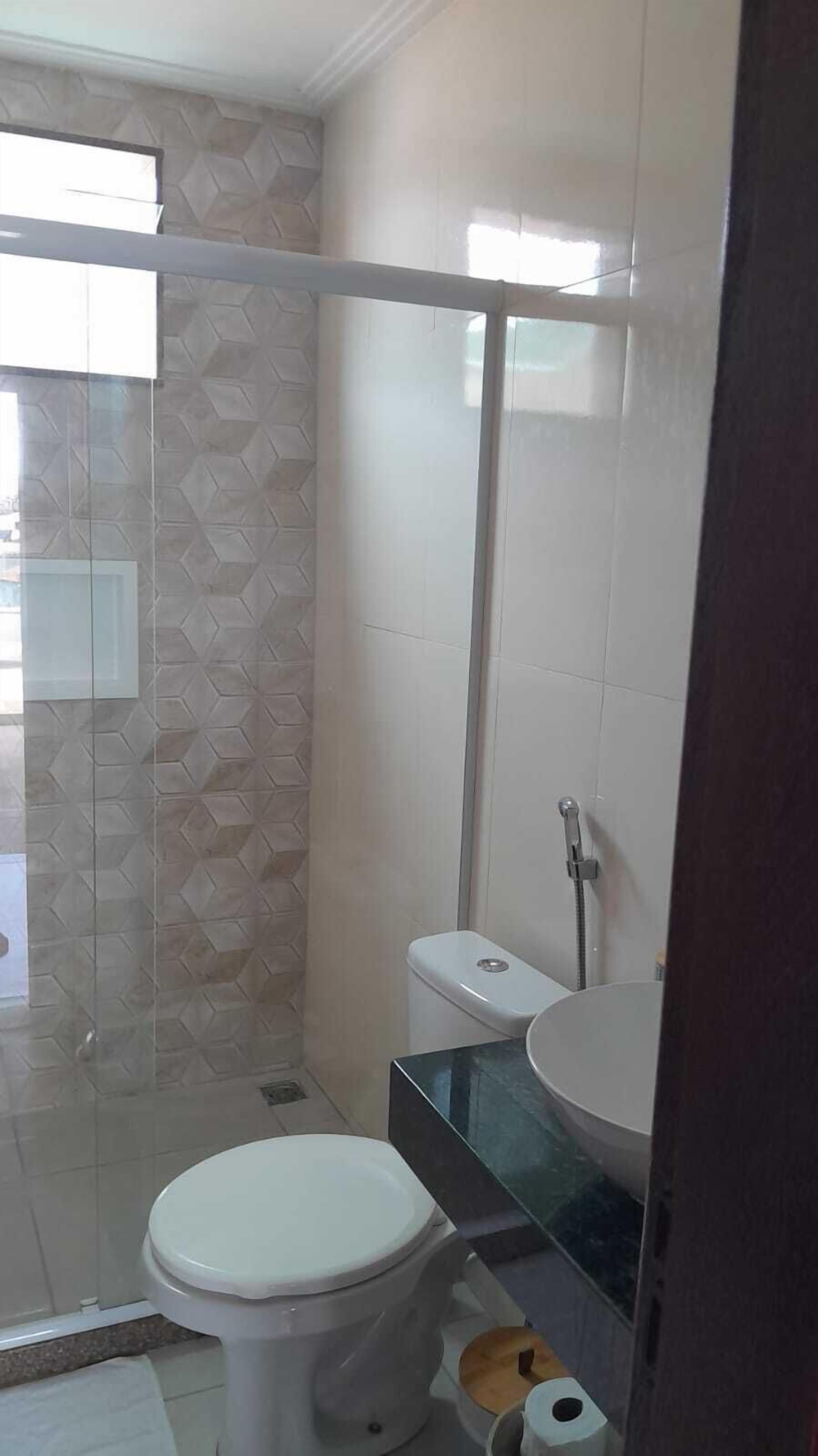 A bathroom with a toilet, a glass shower enclosure, and a sink.