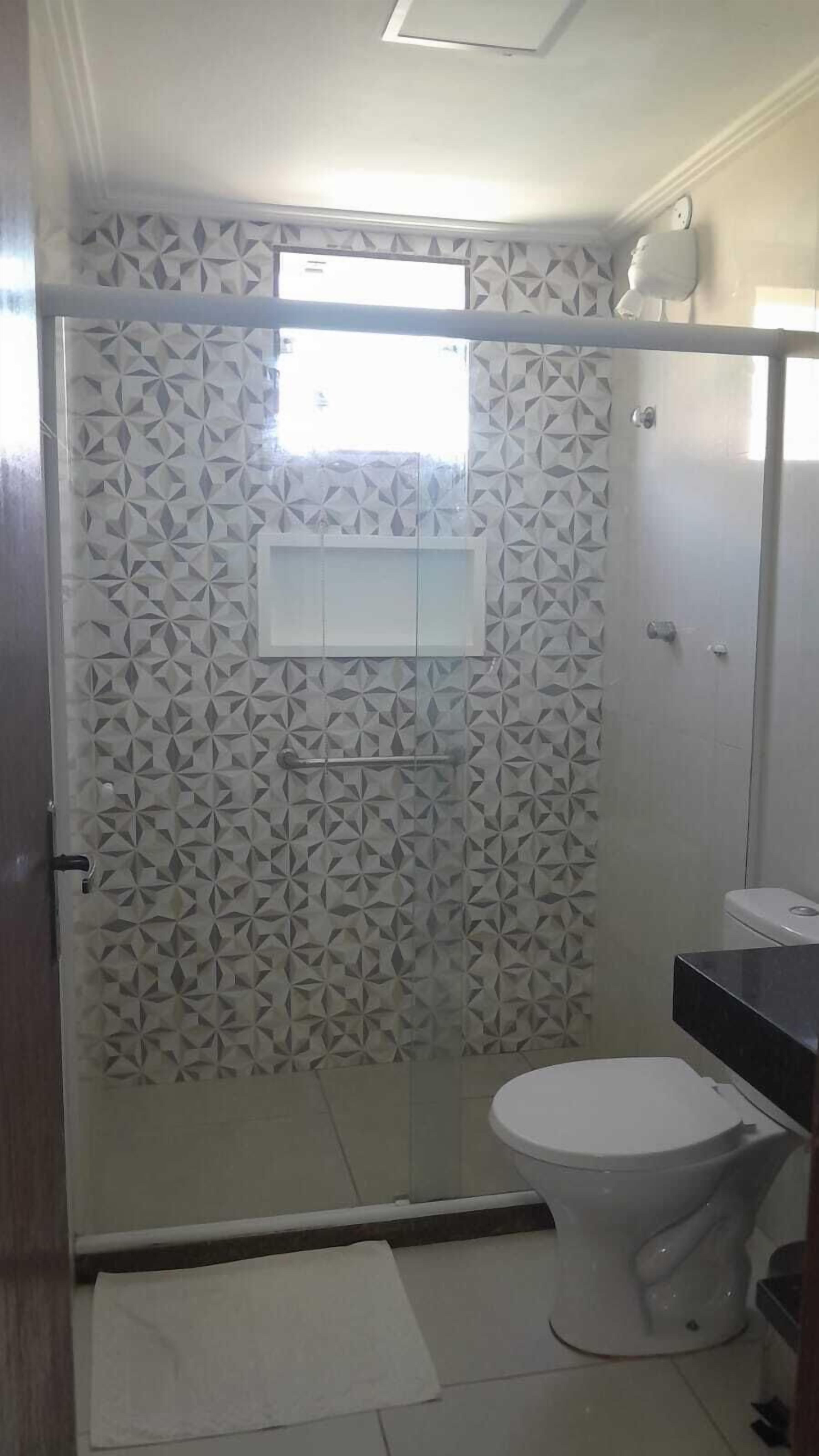 A bathroom with a shower enclosure, a toilet, and a sink.