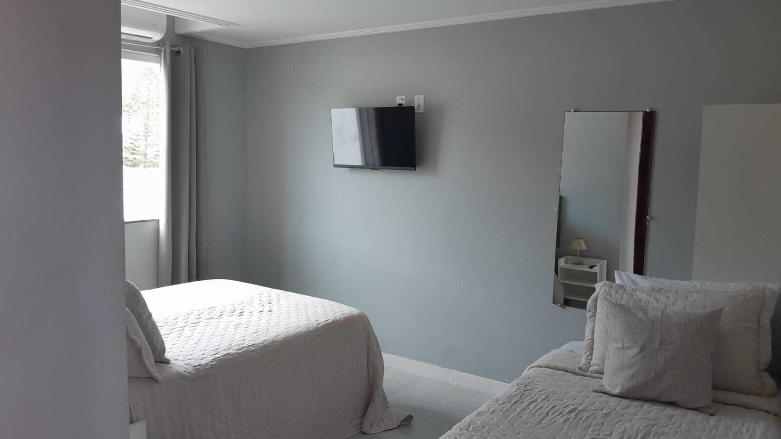 A bedroom with a bed, a TV mounted on the wall, and a mirror.