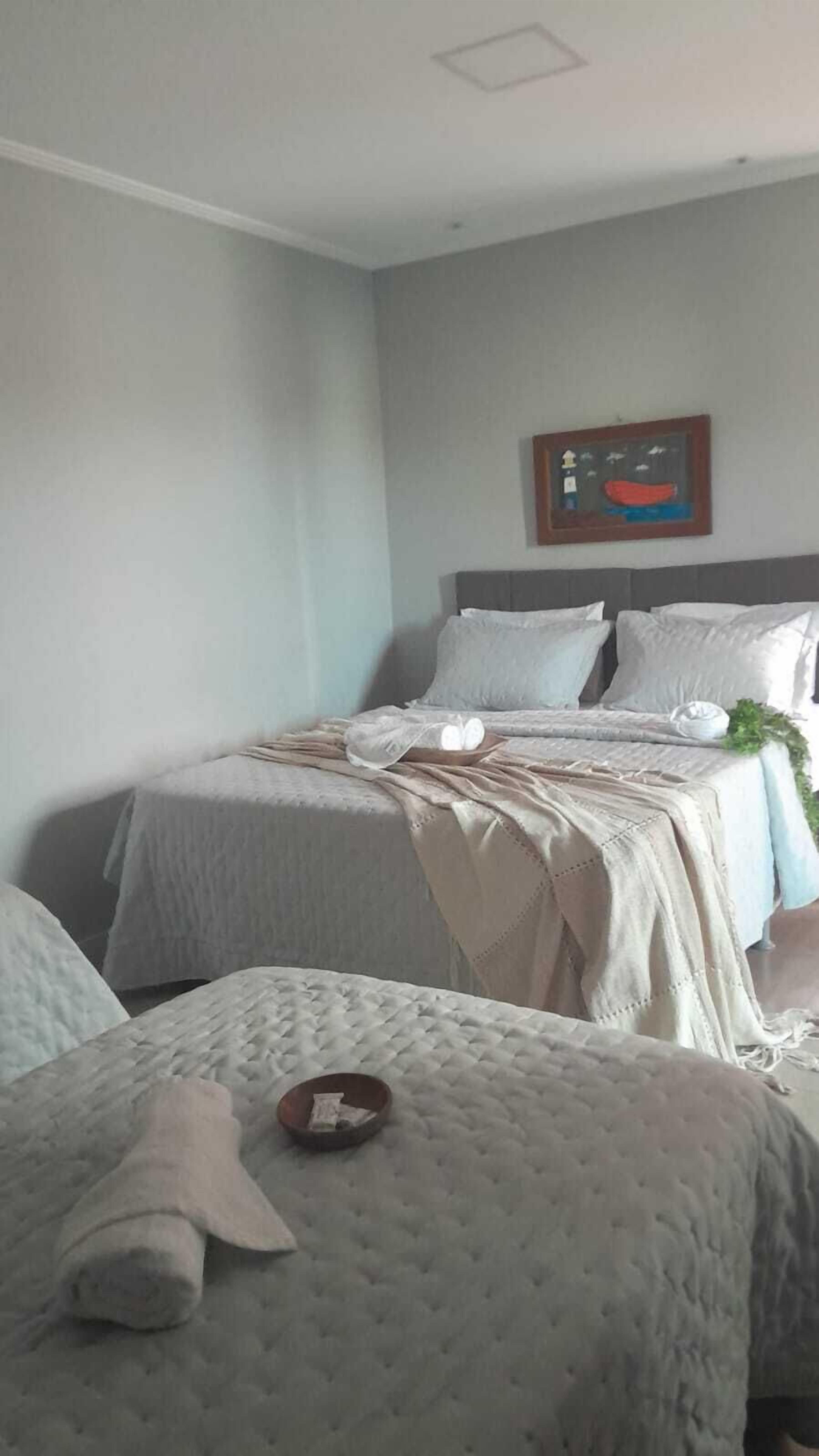 A neatly arranged bedroom with two beds, a framed picture on the wall, and a small table with a towel.