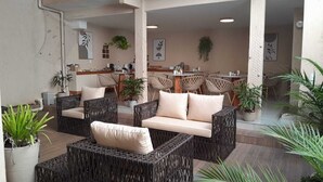 An indoor seating area with wicker furniture and potted plants. - Canoa dos Anjos Suites (Arraial do Cabo)