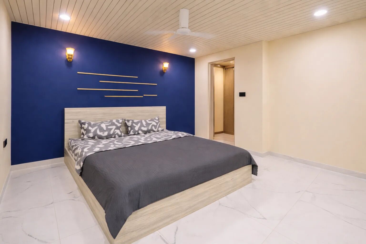 A modern bedroom with a bed, blue accent walls, and a ceiling fan.