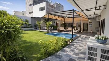 A modern outdoor patio with a pool, seating area, and a covered section.