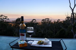 Une table avec une bouteille, un verre de vin rouge et une assiette de fromage et de crackers.
