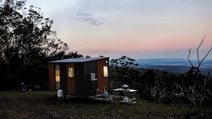 Una cabaña pequeña con una habitación, una mesa y una silla afuera.