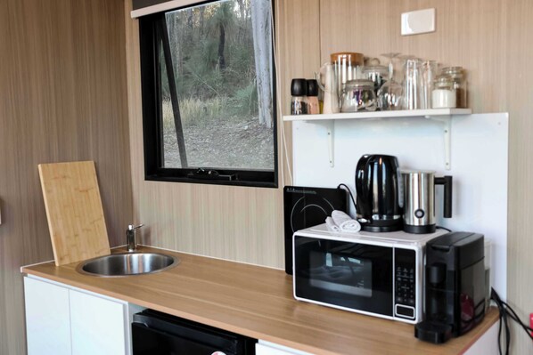 A compact kitchenette with a sink, a microwave, a kettle, and a coffee maker.