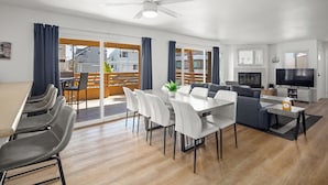 A modern living room with a dining area, a sofa set, a TV, and a ceiling fan. - Mission Beach 10BR · Steps to Bay & Ocean · Water Views · Firetable (San Diego)