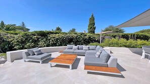 Un espace extérieur moderne, aménagé avec un canapé modulable et une table basse en bois.