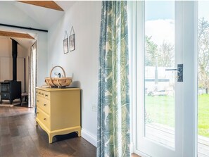 Ein Zimmer mit einer Holzkommode, einem schwarzen Herd und Blick durch eine Glastür.