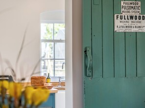 A kitchen with a window, a sink, and a countertop with a bottle and a loaf of bread. - The Cowshed - UK50803 (Cratfield, near Laxfield)