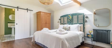 Un dormitorio con cama, armario, radiador y tragaluz.