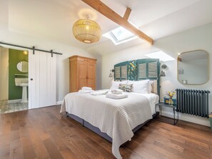 Ein Schlafzimmer mit einem Bett, einem Kleiderschrank, einem Heizkörper und einem Oberlicht.