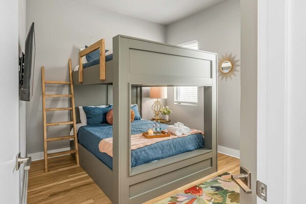 A bunk bed room with a ladder, a bedside table with a lamp, and a mirror on the wall. - Fall getaway: rooftop fire pit, grill & 4BR sleeps 12 in Nashville (Nashville)