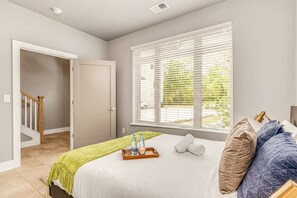 A bedroom with a bed, a window with blinds, a door, and a staircase. - Fall weekend getaway: rooftop deck home sleeps 12 near downtown Nashville (Nashville)