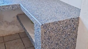 Eine Arbeitsplatte aus Granit mit einem gefleckten Muster, ein integriertes Waschbecken und ein gefliester Boden.