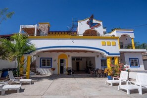 A building with a balcony, a butterfly mural, and a patio area with chairs. - La Casa Mariposa (Rincon de Guayabitos)
