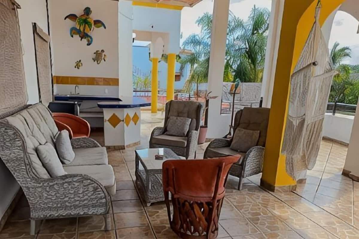 A covered outdoor seating area with sofas, chairs, and a small table.