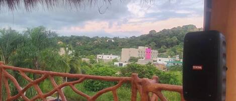 A balcony with a view of a green landscape and buildings.