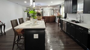 Una cocina moderna con armarios oscuros, una isla central e iluminación colgante.