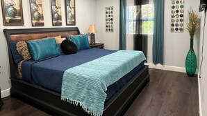 Un dormitorio con cama, ventilador de techo, ventana con cortinas y decoración en la pared.