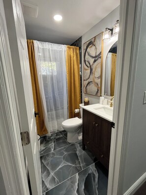 A bathroom with a toilet, a sink, a mirror, and a shower curtain. - The Perfect Place in Spring Hill (Spring Hill)