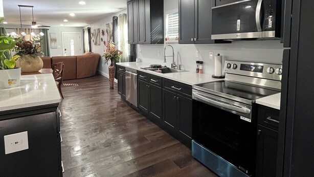 Una cocina moderna con armarios oscuros, electrodomésticos de acero inoxidable y una isla central.