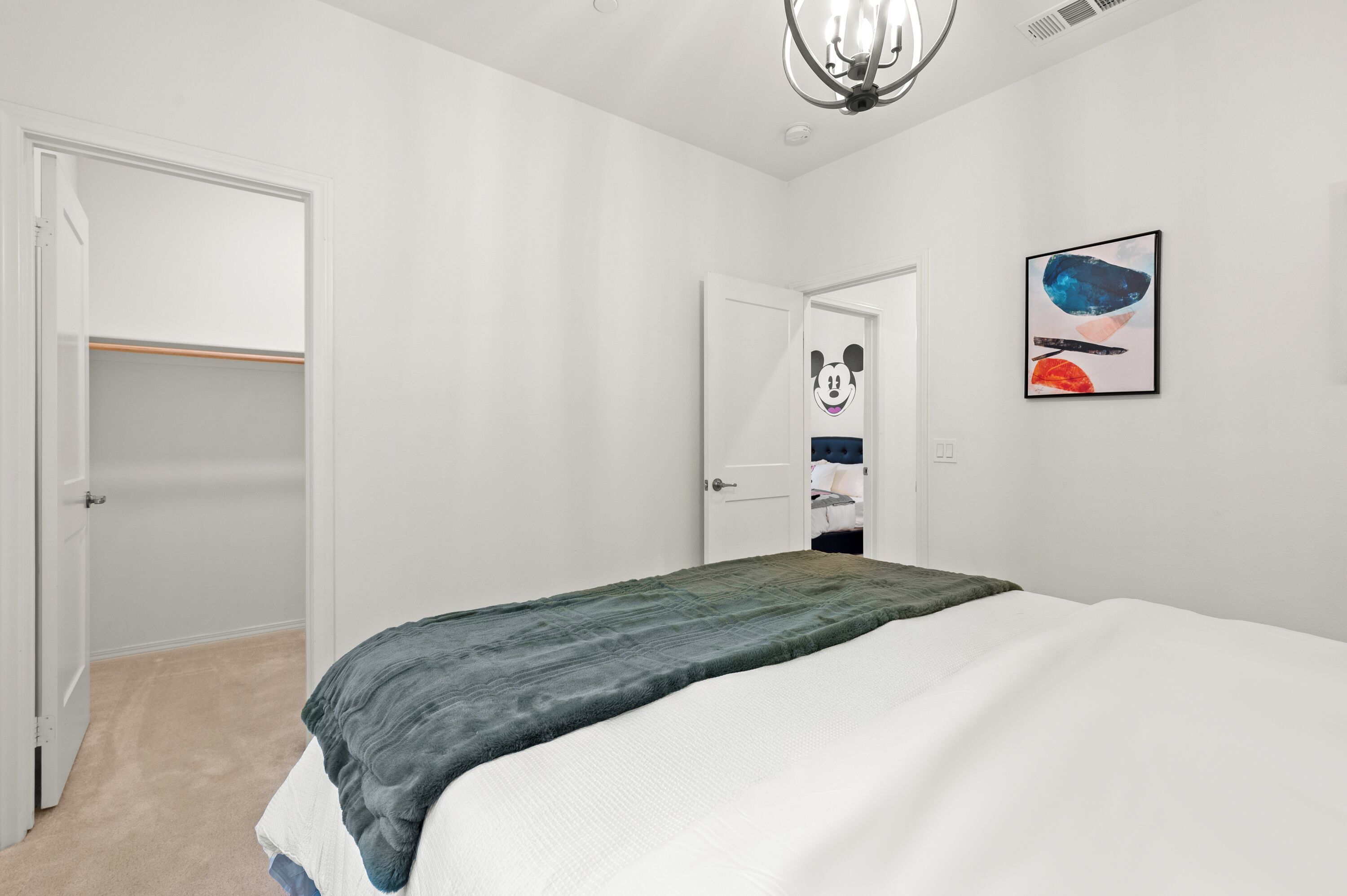 A bedroom with a bed, a closet, and a door leading to another room.