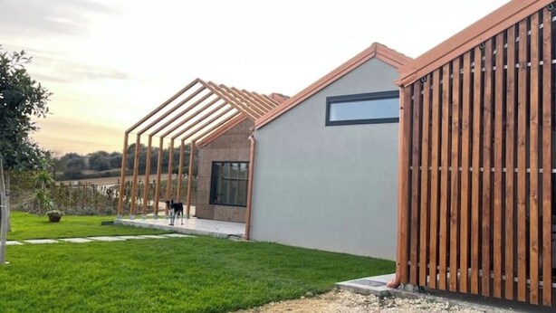 Une maison moderne avec un toit en pente, une clôture en bois et une pelouse bien entretenue.