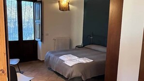 Une chambre à coucher avec un lit, une chaise, un radiateur et une fenêtre avec des rideaux.