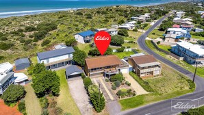 Vista aérea de uma área residencial com casas, ruas e um trecho de costa.
