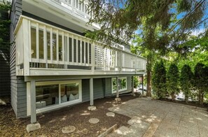 Ein zweigeschossiges Haus mit Balkon, großen Fenstern und einer gepflasterten Auffahrt.