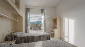 A bedroom with two beds, a balcony with a view of the countryside, and a built-in desk. - CASA SILVIA SUL LUNGOMARE DI CAMPO - SILVIA SUL LUNGOMARE DI CAMPO (Campo nell'Elba)