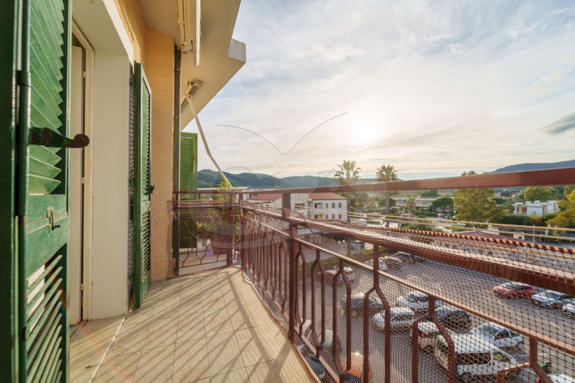 Ein Balkon mit Blick auf einen Parkplatz und Gebäude in der Ferne.