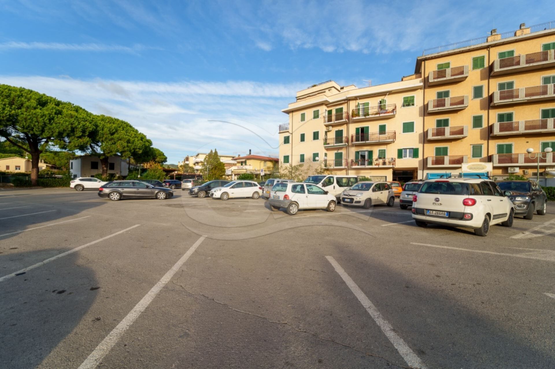 Ein Parkplatz mit mehreren Autos und einem mehrstöckigen Gebäude im Hintergrund.