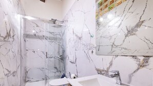 Een badkamer met een douchecabine van glas, een toilet en een wastafel met een spiegel erboven.