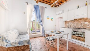 A cozy kitchen with a dining table, a sofa, and a window with curtains.