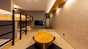 Una habitación de hotel con literas, una mesa redonda de madera y un televisor.