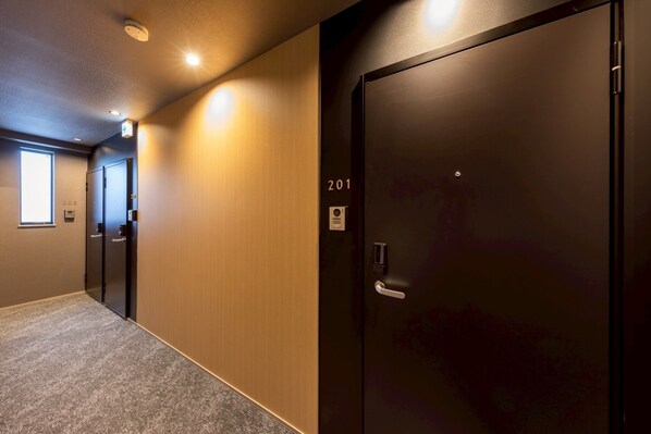 A hallway with a carpeted floor, a door labeled "201", and a window on the left.