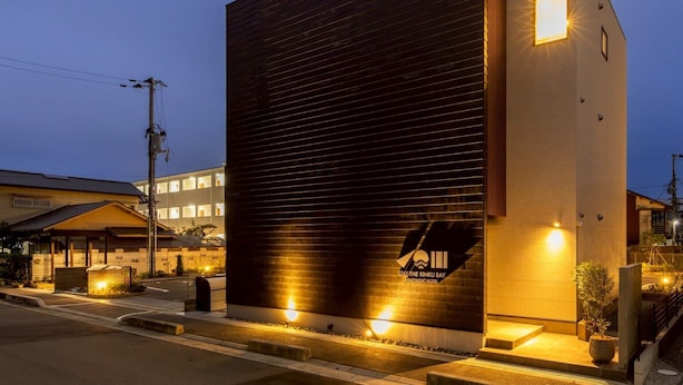 Un edificio moderno con fachada oscura y un letrero iluminado del Rinku Bay Apartment Hotel.