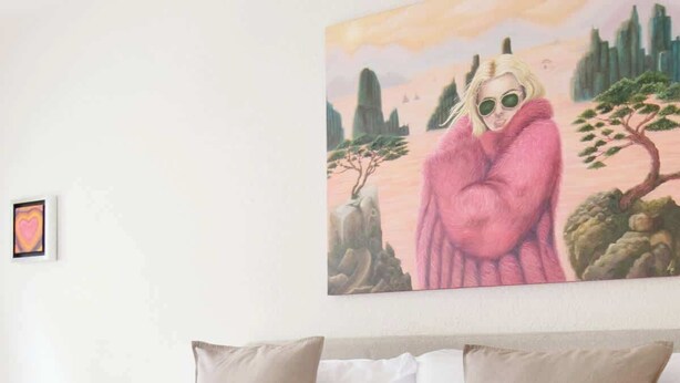 Ein Schlafzimmer mit Bett, Kissen, einem Tablett mit Speisen und Getränken sowie einem Gemälde an der Wand.